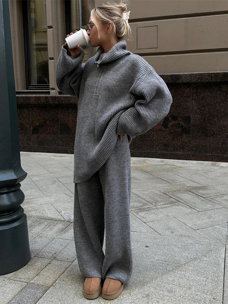 Woman wearing grey ribbed half-zip turtleneck sweater with matching wide-leg knit trousers, VOHRAN co-ord set